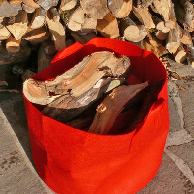 SACKGSUND – der naschgarten im sack. Die Abbildung zeigt einen SACKGSUND Pflanzsack in rot als Transportbehältnis für Brennholz